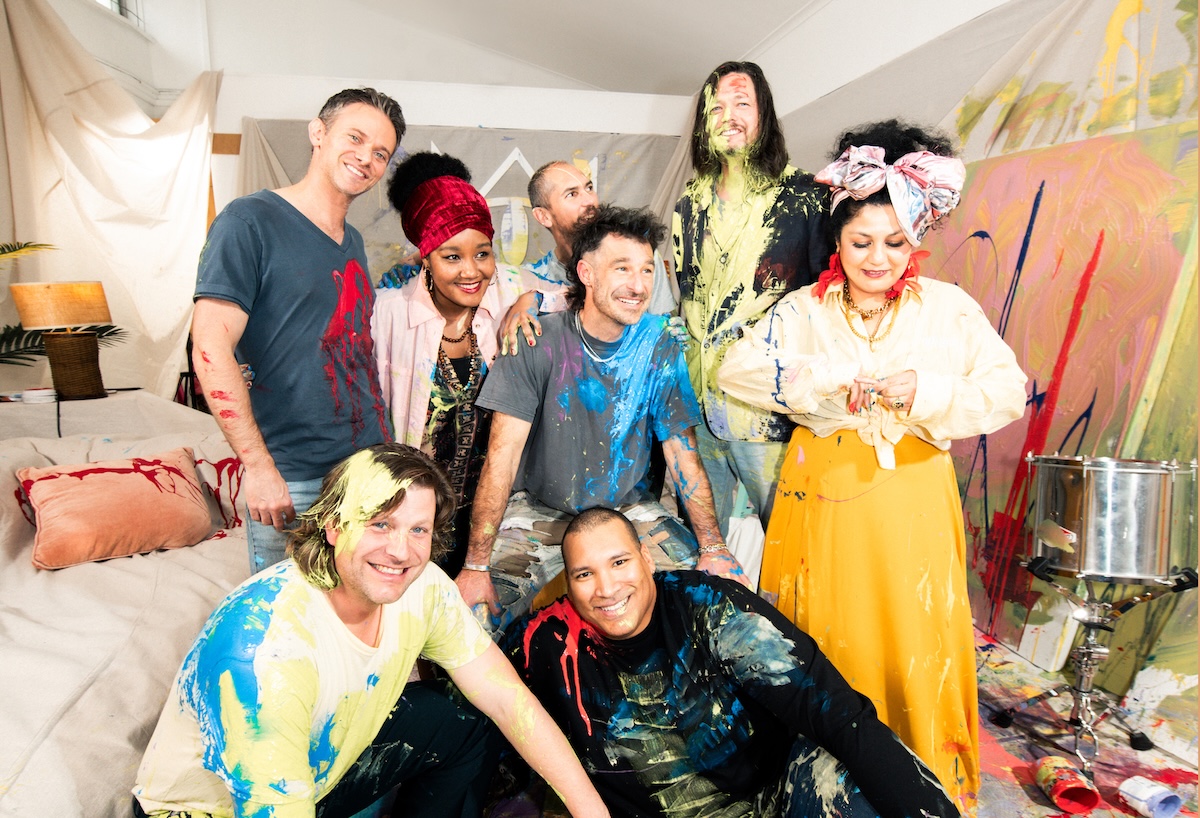 Australian band The Cat Empire members covered in colourful paint posing together in an art studio captured by Giulia McGauran